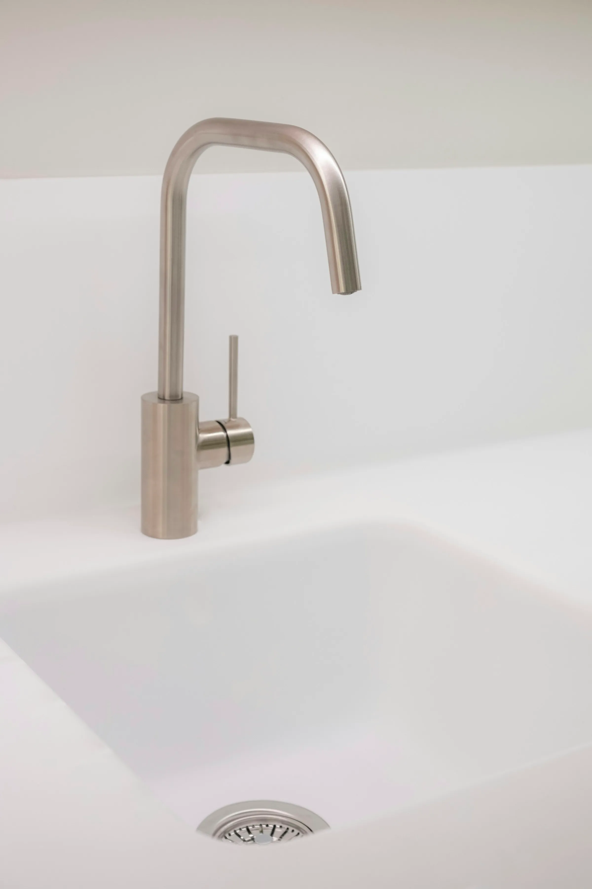 Close-up of a white sink formed into the countertop with no visible joint, below a brushed steel tap
