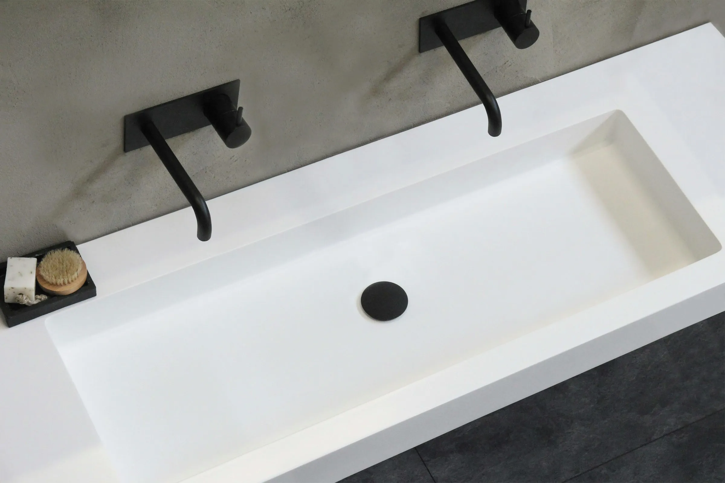 White vanity top with a built-in trough basin and matte black wall-mounted taps